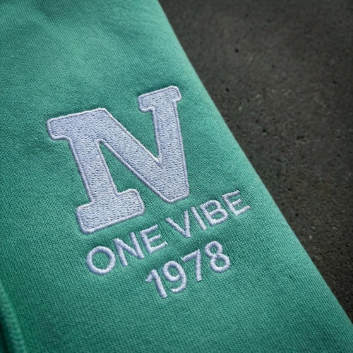 Detail van geborduurd One Vibe 1978 logo wit op mintgroen hoodie.